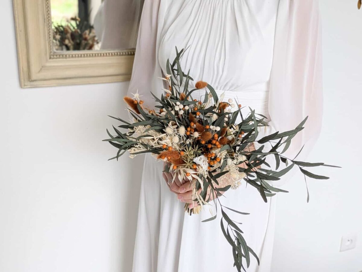 Bouquet de mariée en fleurs séchées et stabilisées aux teintes terra cotta, vert eucalyptus et beiges.