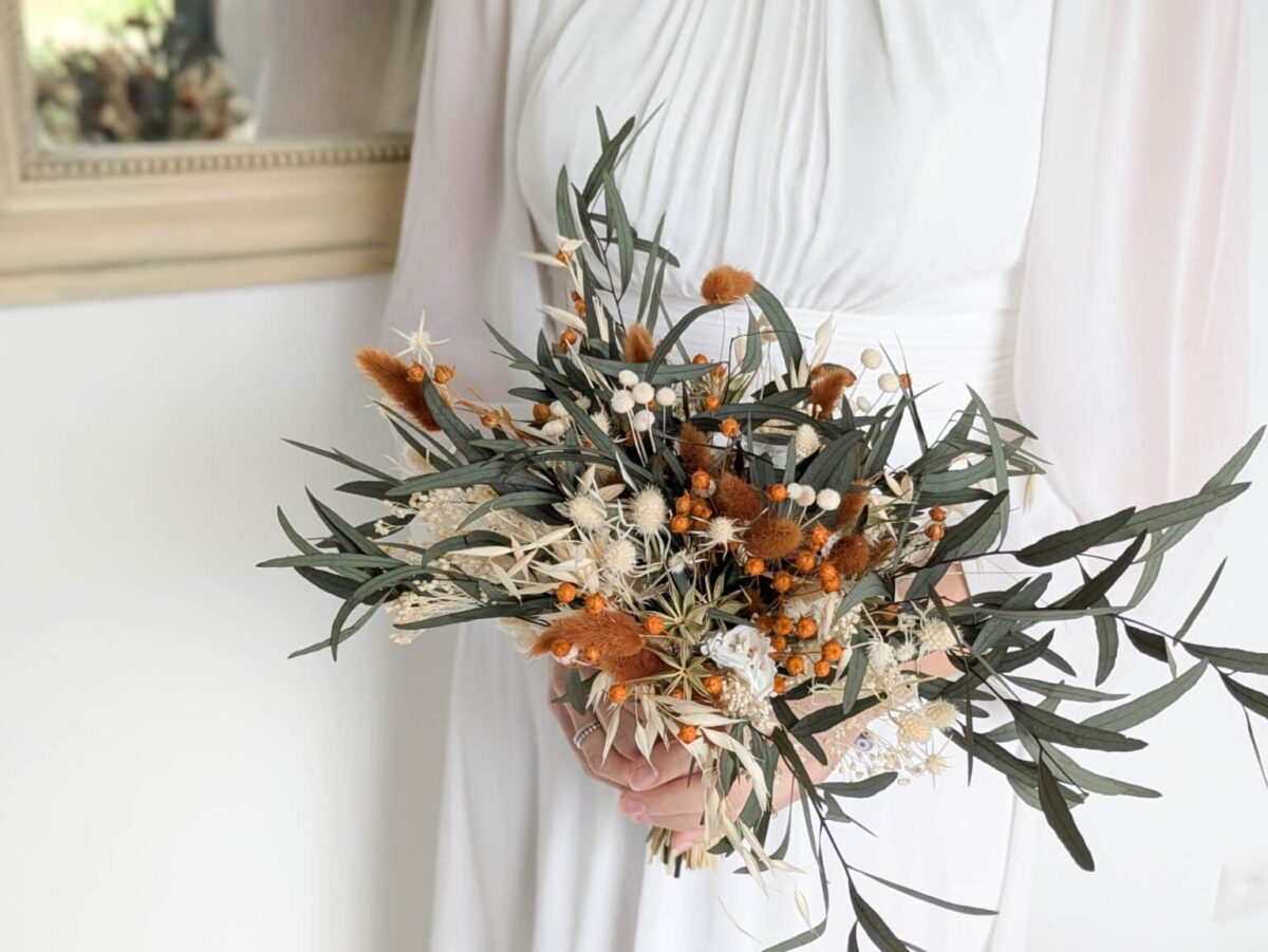 Bouquet de mariée en fleurs séchées et stabilisées aux teintes terra cotta, vert eucalyptus et beiges.