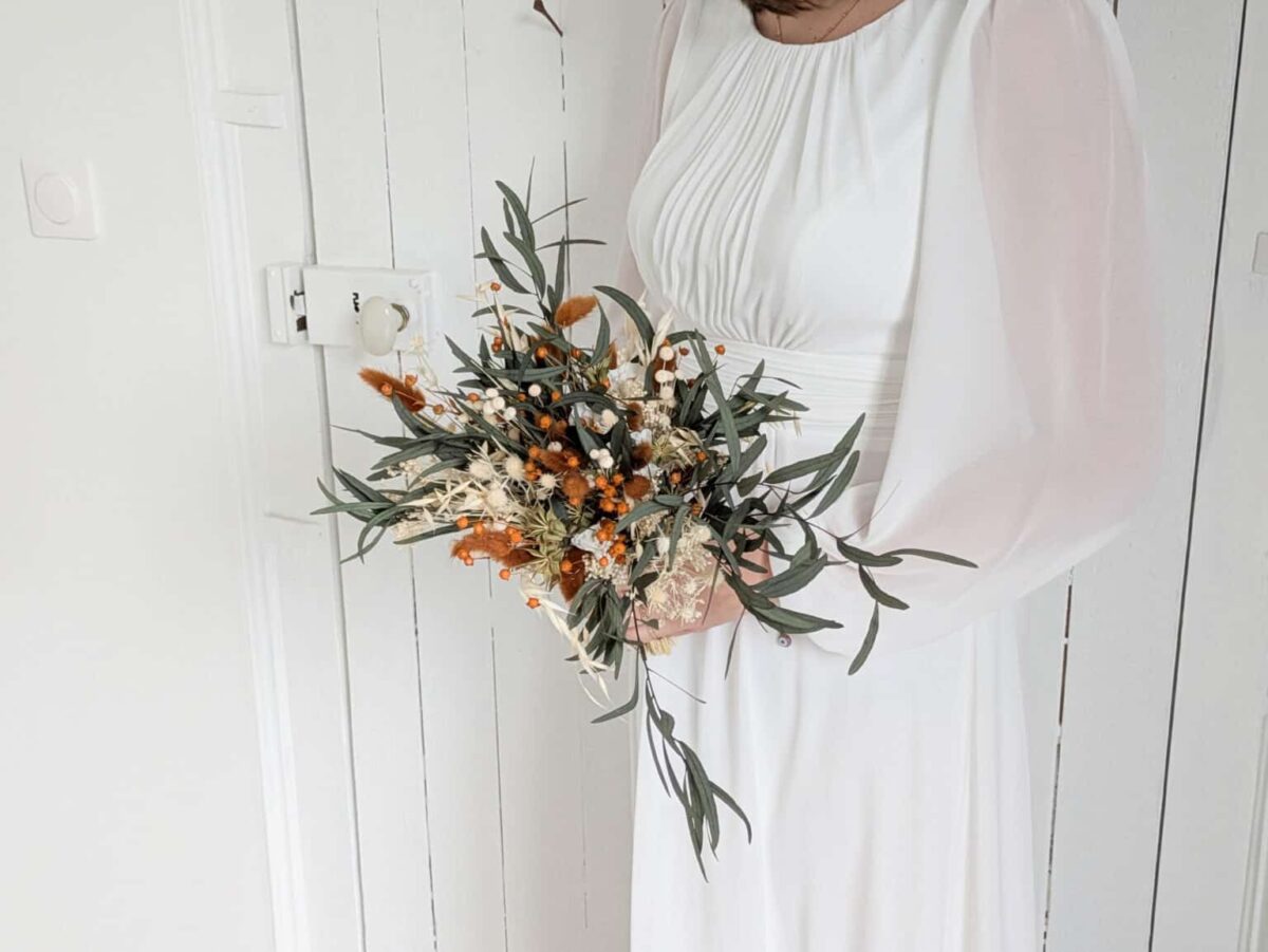 Bouquet de mariée en fleurs séchées et stabilisées aux teintes terra cotta, vert eucalyptus et beiges.