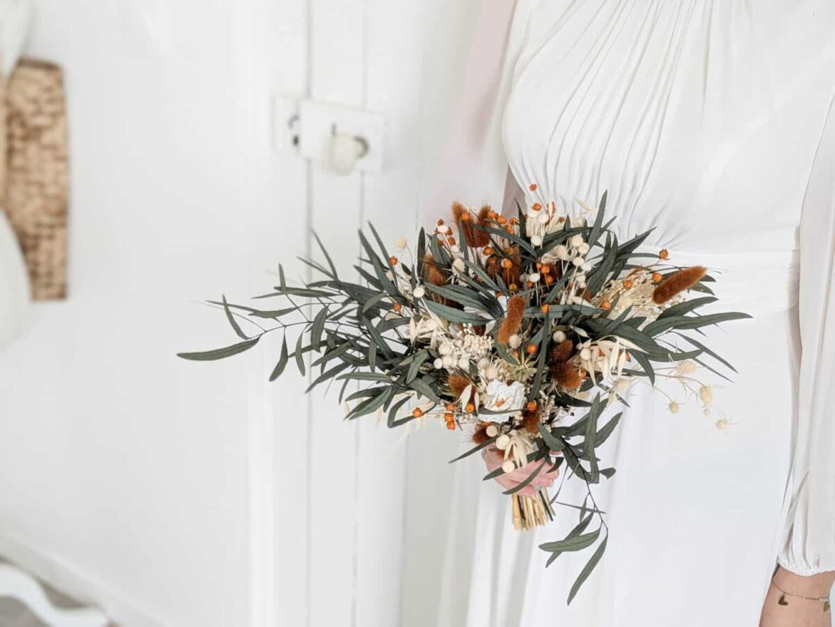 Bouquet de mariée en fleurs séchées et stabilisées aux teintes terra cotta, vert eucalyptus et beiges.