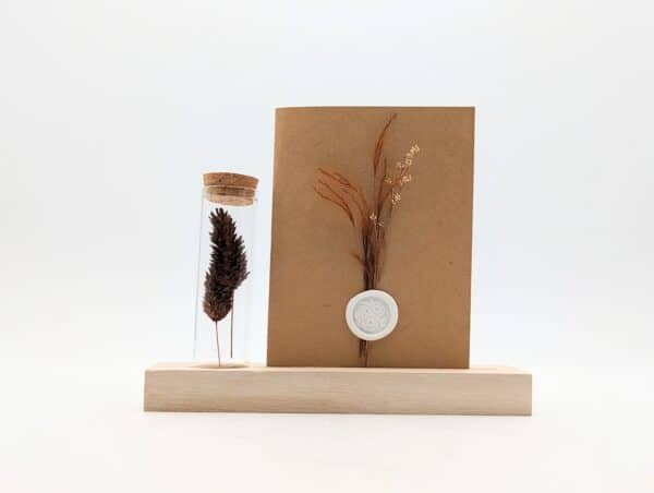 Porte carte en bois avec une éprouvette en fleurs séchées terracotta, carte en kraft brun avec fleurs séchées terracotta et cachet de cire.