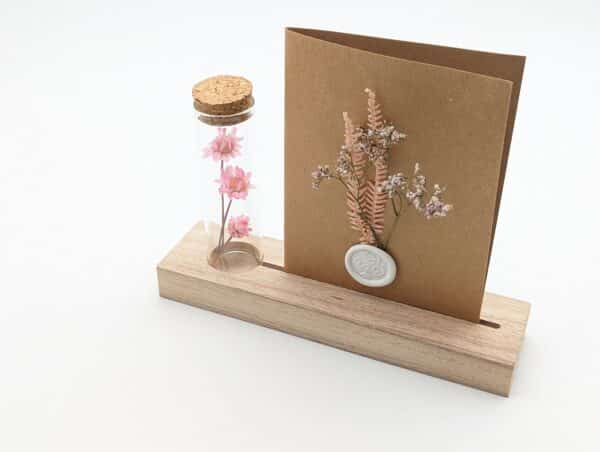 Porte carte en bois avec une éprouvette en fleurs séchées roses , carte en kraft brun avec fleurs séchées roses et cachet de cire.