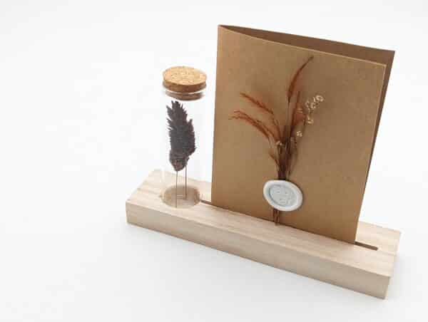 Porte carte en bois avec une éprouvette en fleurs séchées terracotta, carte en kraft brun avec fleurs séchées terracotta et cachet de cire.