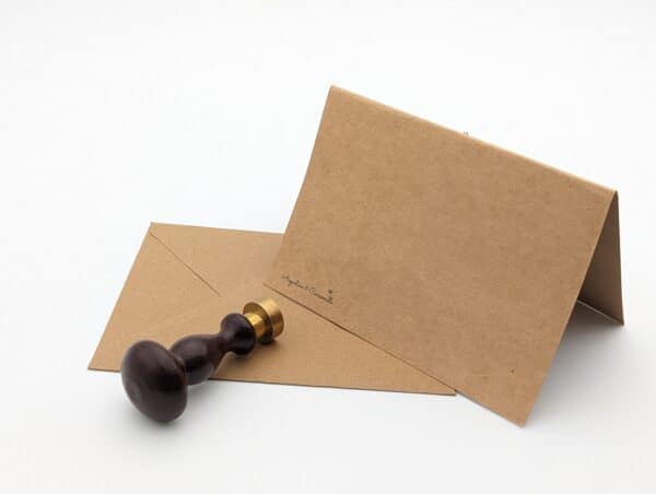 Carte en kraft brun avec fleurs séchées et cachet de cire avec enveloppe.