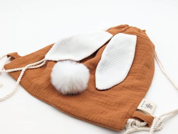 Petit sac pour enfant en double gaze de coton châtaigne avec oreille de lapin et queue de lapin en fourrure blanche.