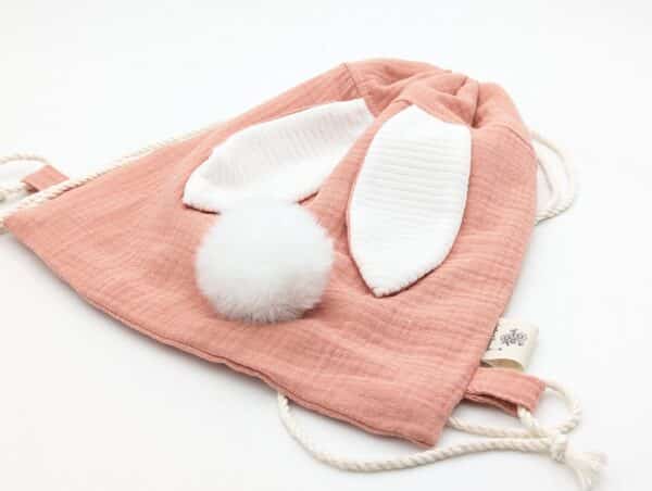 Petit sac pour enfant en double gaze de coton rose avec oreille de lapin et queue de lapin en fourrure blanche.
