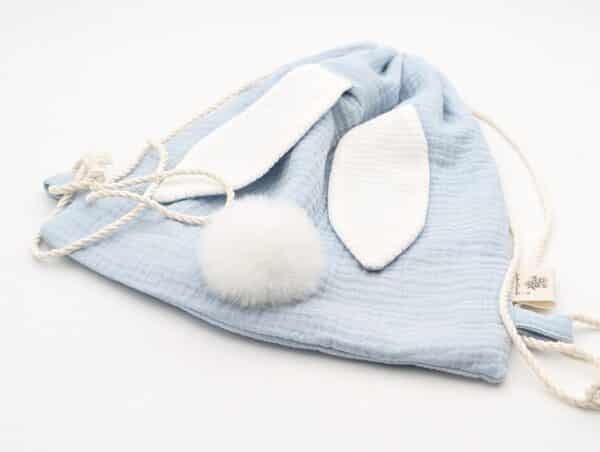 Petit sac pour enfant en double gaze de coton bleu ciel avec oreille de lapin et queue de lapin en fourrure blanche.