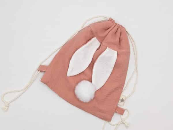 Petit sac pour enfant en double gaze de coton rose avec oreille de lapin et queue de lapin en fourrure blanche.