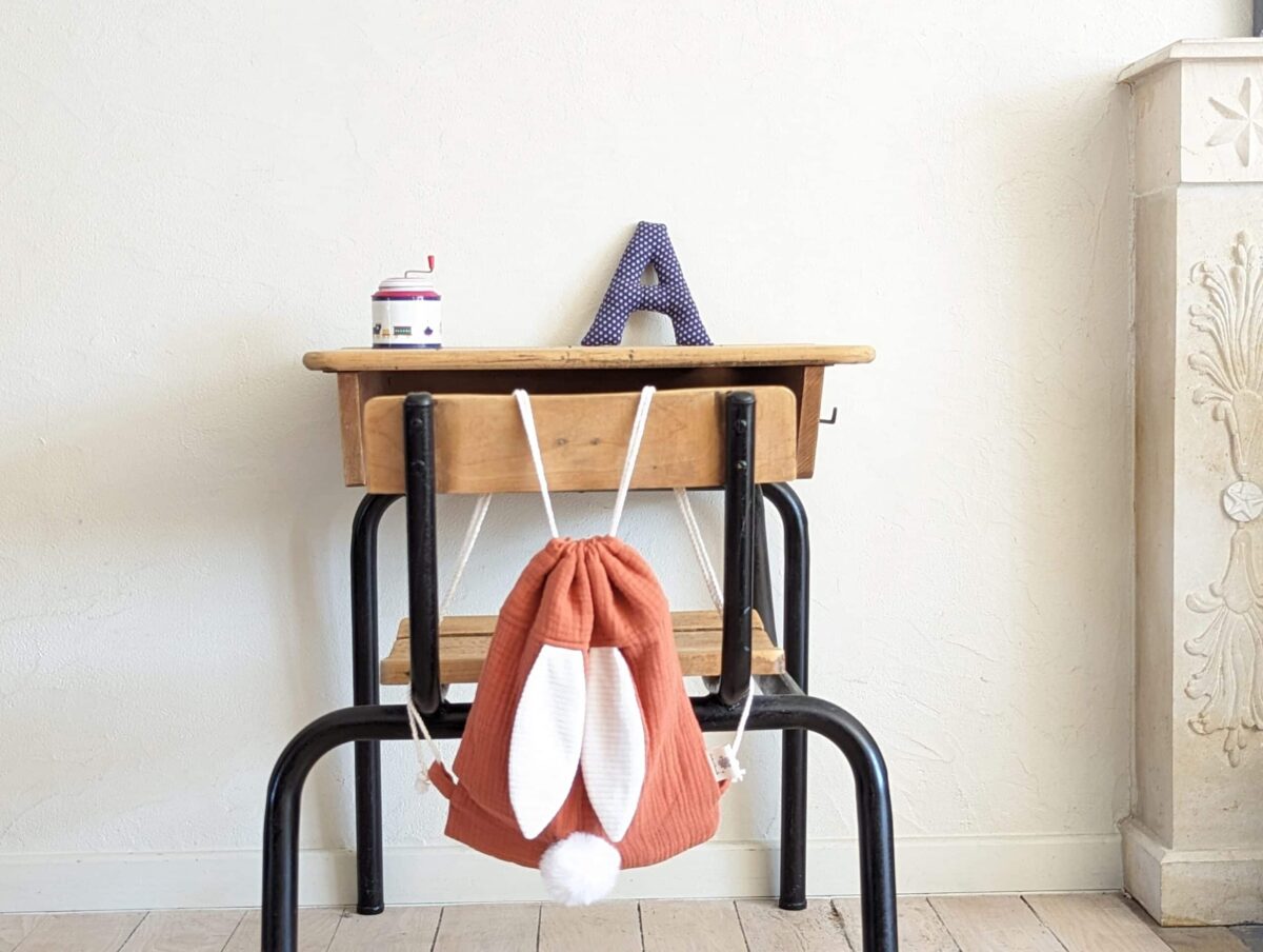 Petit sac pour enfant en double gaze de coton terracotta avec oreille de lapin et queue de lapin en fourrure blanche.