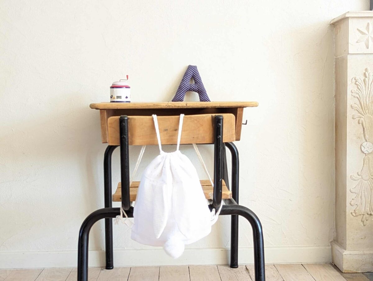 Petit sac pour enfant en double gaze de coton blanc avec oreille de lapin et queue de lapin en fourrure blanche.