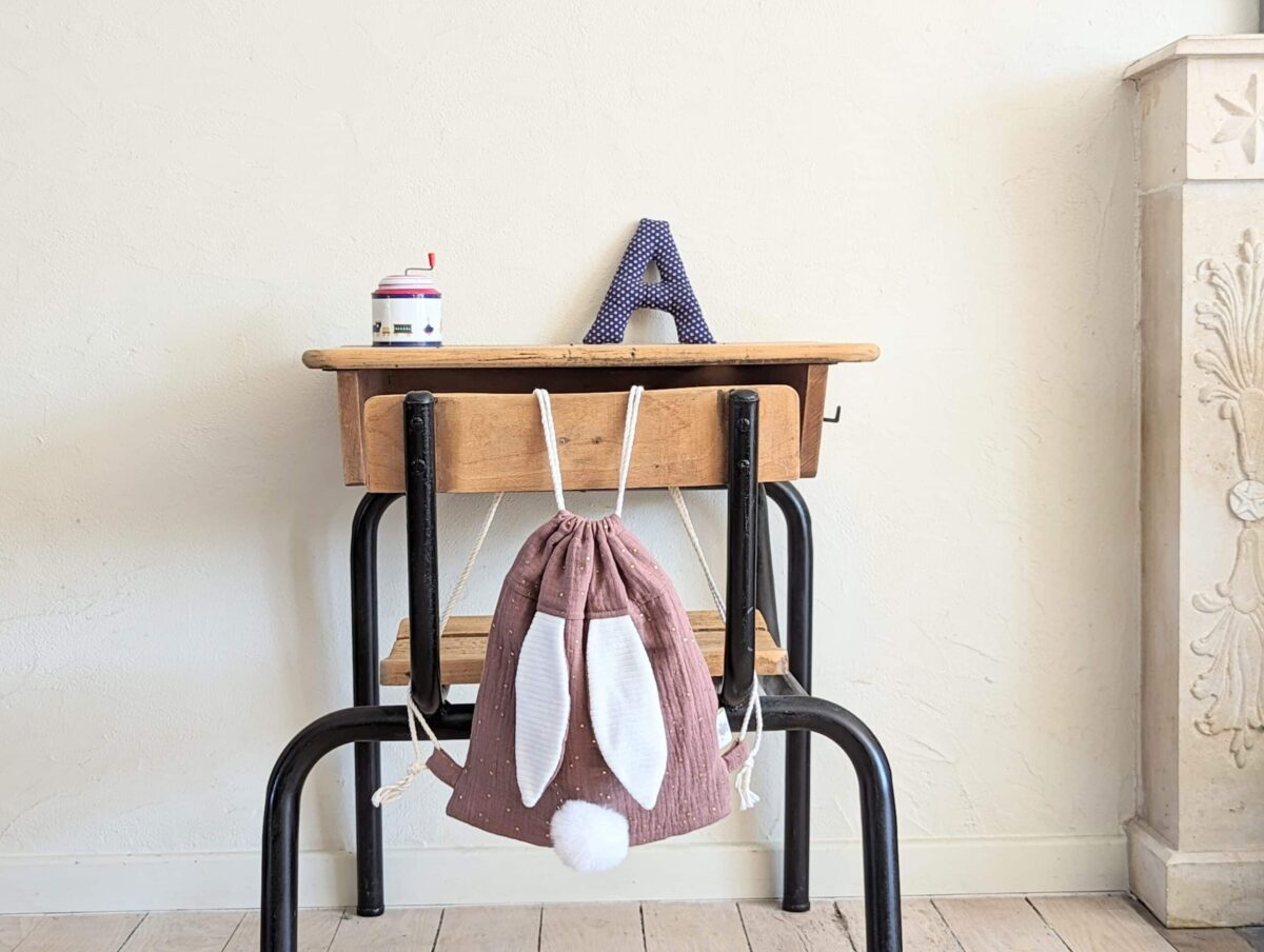 Petit sac pour enfant en double gaze de coton prune avec oreille de lapin et queue de lapin en fourrure blanche.