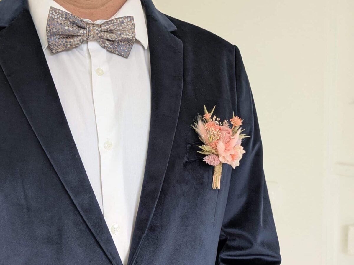 boutonnière mariage en fleurs séchées garçon d'honneur, témoin, marié, enfant de couleur ton rose romantique s'accroche avec son épingle à nourrice